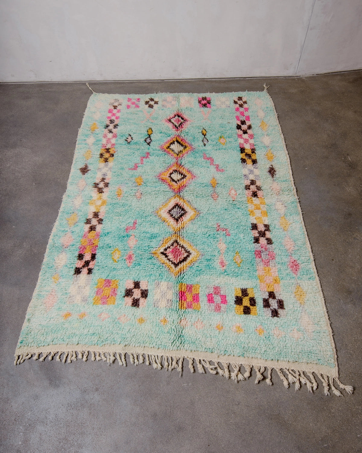 Berberlin Vintage Berber Rug made of fluffy turquoise wool, photographed on grey concrete floor.